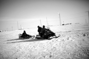 Local veterans representative Sean Komonaseak drives a snowmobile with Tommy Sowers (back seat) and Sean Foertsch across the ice to the village of Wales, Alaska.