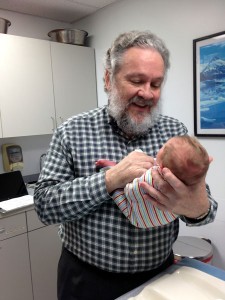 Dr. Charles Ryan holds an infant after a circumcision. Photo by Annie Feidt, APRN - Anchorage.