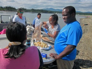 Kevin Foster (right) watches as lunch is prepared during a stop at a beach along the Kobuk River. Photo by Daysha Eaton, KSKA - Anchorage.