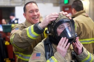 Firefighter Joe Mishler helps place on Juneau Assembly member Kate Troll’s oxygen mask at Hagevig Fire Training Center. (Photo by Annie Bartholomew/KTOO)