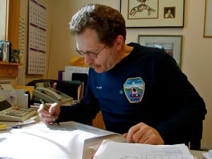 Dave Berg looks over a spread sheet of this year’s visitors at Viking Travel, Inc. (Photo by Angela Denning, KFSK - Petersburg)
