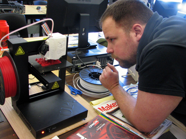 Metlakatla Science teacher Jason Pipkin watches as the printer creates metric screws for a quadcopter his students are building. (KCAW photo/Robert Woolsey)