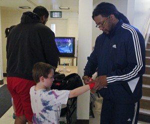 Coach Michael Carey helps a young boxer with his gloves. (Photo by Josh Edge, APRN - Anchorage)