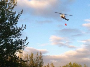 A helicopter drops water on the fire near Soldotna Monday night (Ariel Van Cleave photo)