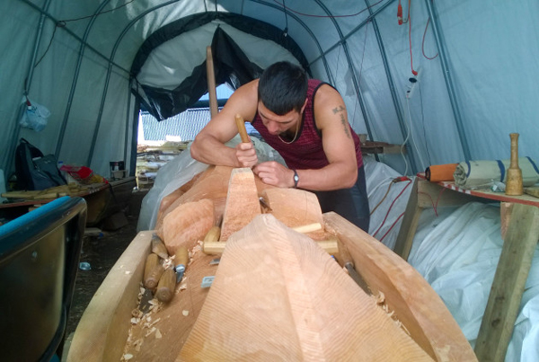 Haida carver T.J. Young carves fine details into an Eagle totem pole in progress. (Photo by Jeremy Hsieh/KTOO)