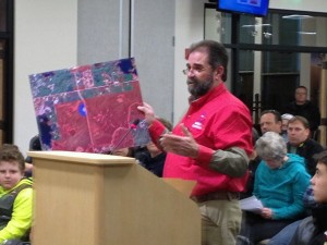 Neil Moss, president of Alaska Scholastic Clay Target Program,  holds up a map of land the ASCTP wants for a shooting range at the Matanuska-Susitna Borough Assembly meeting on Tuesday. (Photo by Ellen Lockyer, KSKA - Anchorage)