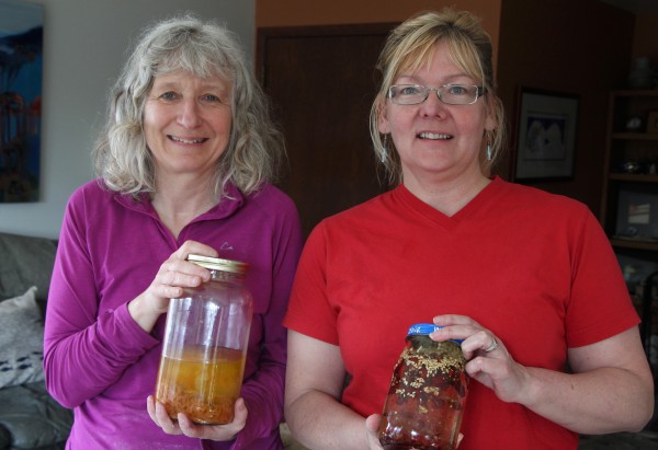 Denise Lisac and Lynn Van Vactor holding carrot and rose hip infusions. (Photo by Hannah Colton, KDLG – Dillingham) 
