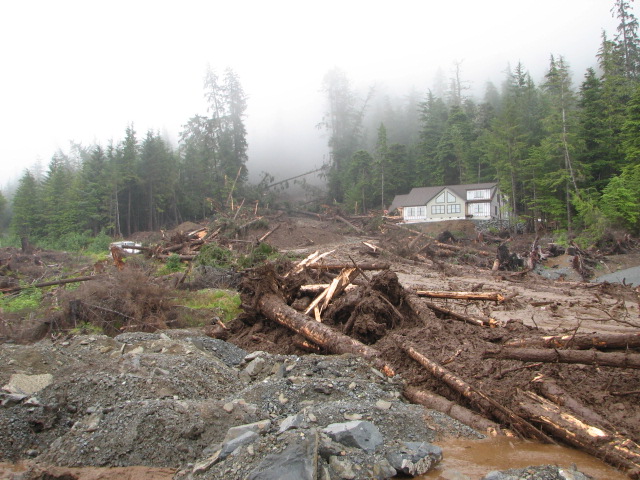 A new home under construction on Sitka’s Kramer Avenue was obliterated in the slide. A neighboring home is unscathed. (Photo by Joel Curtis/National Weather Service)