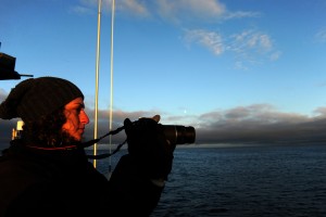 Katherine Robbins photographs the sunset from the US Fish and Wildlife Service research boat R/V Tiglax as sails from Adak Islands on a cruise to Attu Island in the Aleutian Islands, in western Alaska, on Sunday, May 31, 2015. Robbins from Memorial University of Newfoundland in St. John Newfoundland will be dropped of at Buldir Island where she will be studying Auklets. (Bob Hallinen / Alaska Dispatch News)