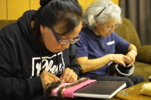Stacey Skan and Anna Frisby sew sea otter fur onto knit headbands as a donation to Hydaburg’s Artist Co-op. Photo: Ruth Eddy/KRBD.