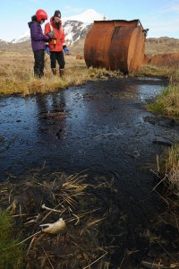 Former KUCB radio reporter Lauren Rosenthal and Biologist Jeff Williams inspect the black substance leaking from tanks on Attu Island as the US Fish and Wildlife Service research boat R/V Tiglax stops at the western most of the Aleutian Islands on Wednesday, June 3, 2015. (Bob Hallinen / Alaska Dispatch News)