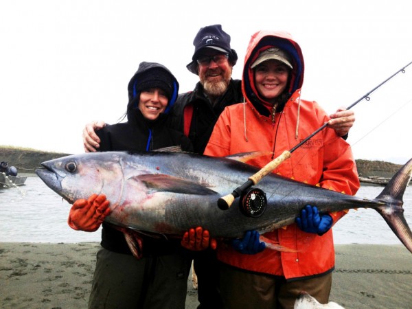 Wait, that’s not a salmon. Alaska Department of Fish and Game’s Nicole Zeiser, sport fish guide Terry Wheeler, and commercial set gillnet fisherman Kaytlynn Graber pose with a nearly 80-pound yellowfin tuna found near the Tsiu River in 2013. Zeiser says Graber and her husband Brant Graber found the tuna lying dead on the beach. (Photo courtesy of Nicole Zeiser, Alaska Department of Fish and Game)