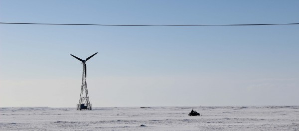 A snowmachine racing past one of Kwigillingok's wind turbines. Photo: Rachel Waldholz/APRN