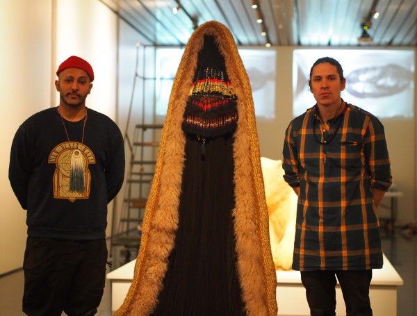 Nicholas Galanin, left, with his collaborator Nep Sidhu standing beside a piece in the "Kill The Indian, Save The Man" exhibit. Photo: Zachariah Hughes.