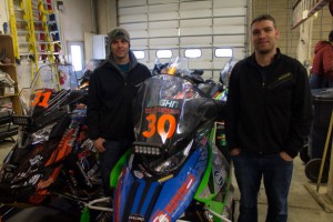 Iron Dog Team #30 Jerrod Vaughn and Geoff Crouse with their machines in the garage. (Photo: Emily Russell/KNOM)