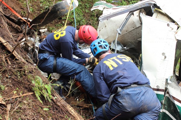NTSB investigators Brice Banning and Clint Crookshanks on scene near Ketchikan examining the wreckage of a sightseeing plane that crashed in Alaska on June 25, 2015. This is not one of the crashes featured in the new TV series. (Creative Commons photo by National Transportation Safety Board)
