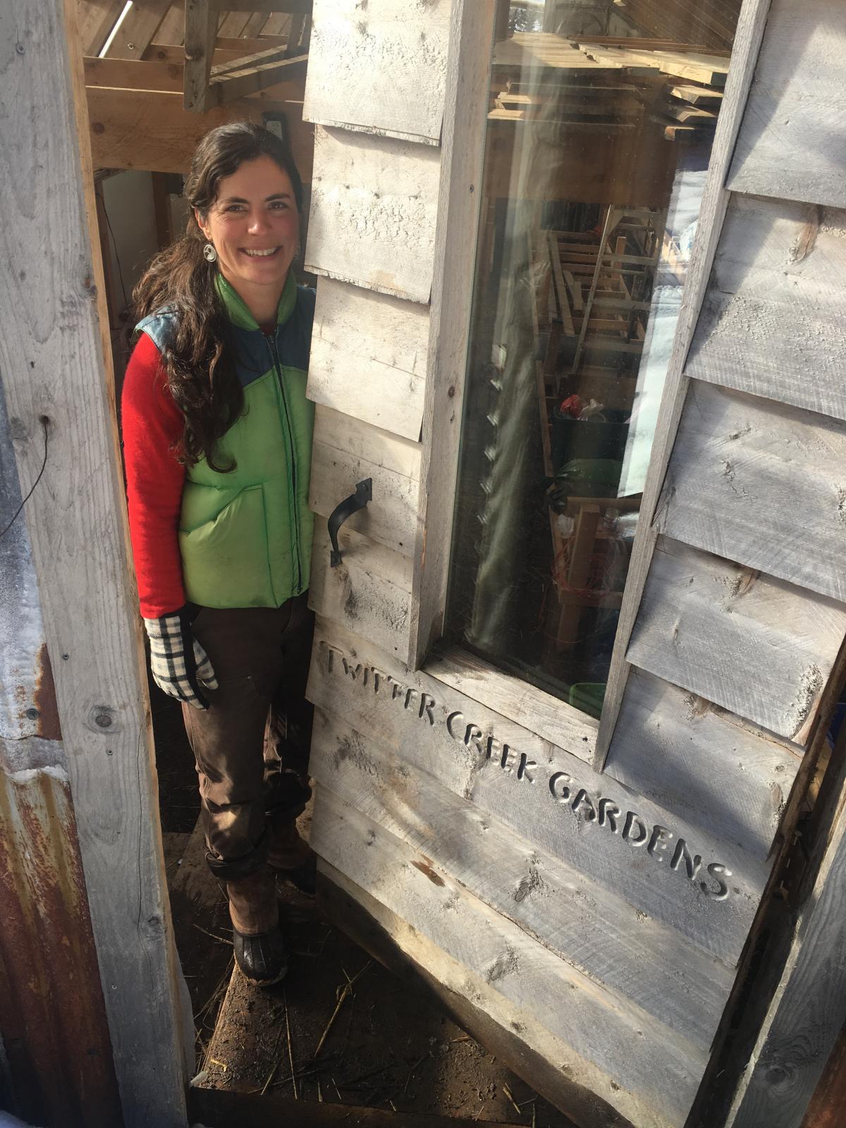 Emily Garrity peeks out from the door of her greenhouse at Twitter Creek Gardens on Ohlson Mountain outside Homer.( Photo by Daysha Eaton, KBBI - Homer)