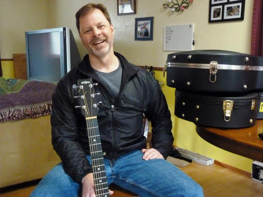 Juneau guitarist, singer and songwriter Kray Van Kirk talks about his music in his dining room, next to his guitar cases. He'll perform during the Alaska Folk Festival, April 4-11 in Juneau. (Photo by Ed Scheonfeld - CoastAlaska - Juneau)