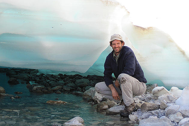 Mark Urban shown under a sheet of auefis in Alaska. These ice sheets form over Arctic underground springs but have become less prevalent with global warming. (Photo courtesy of Mark Urban)
