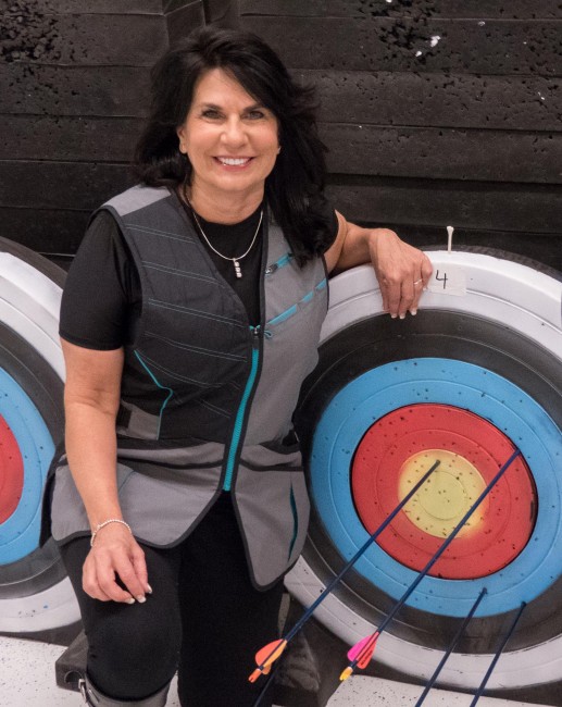 Cathy Tilton poses in front of her target at the Juneau Hunter Education Shooting Complex during the 19th Annual Legislative Team Shoot. (Photo by David Purdy, KTOO - Juneau)