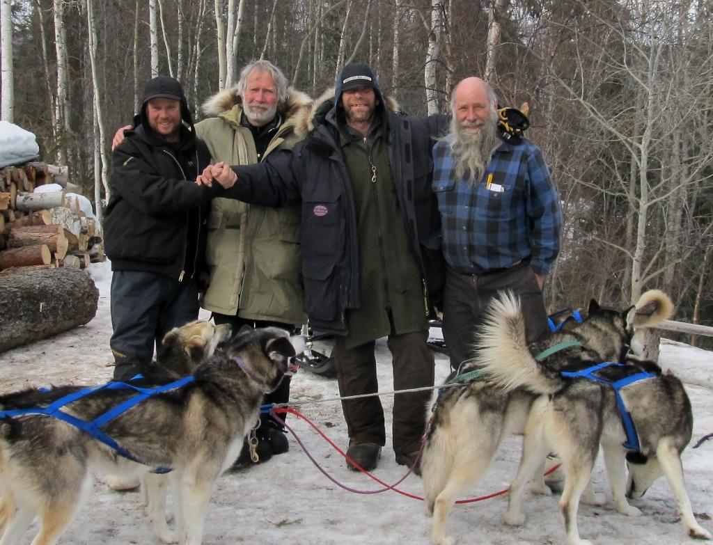 Expedition members celebrate their success upon arrival in Eagle. Front row: "the real heroes" – the dogs that pulled the three sleds over the 700-mile journey. Back row, from left: Graham Burke, Tim Oakley, Wayne Hall and Earl Rolf, who broke trail and ferried supplies to caches along the route. (Photo courtesy of inamundsensfootsteps.com)