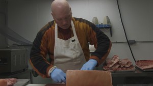Joe Harvey cuts meat at the Point Mackenzie Correctional Farm. (Norris/Alaska Public Media)