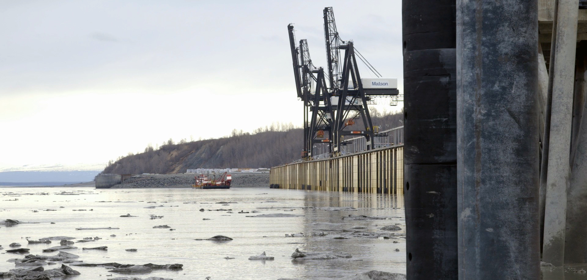pilings along a body water, two container cranes and a cargo ship