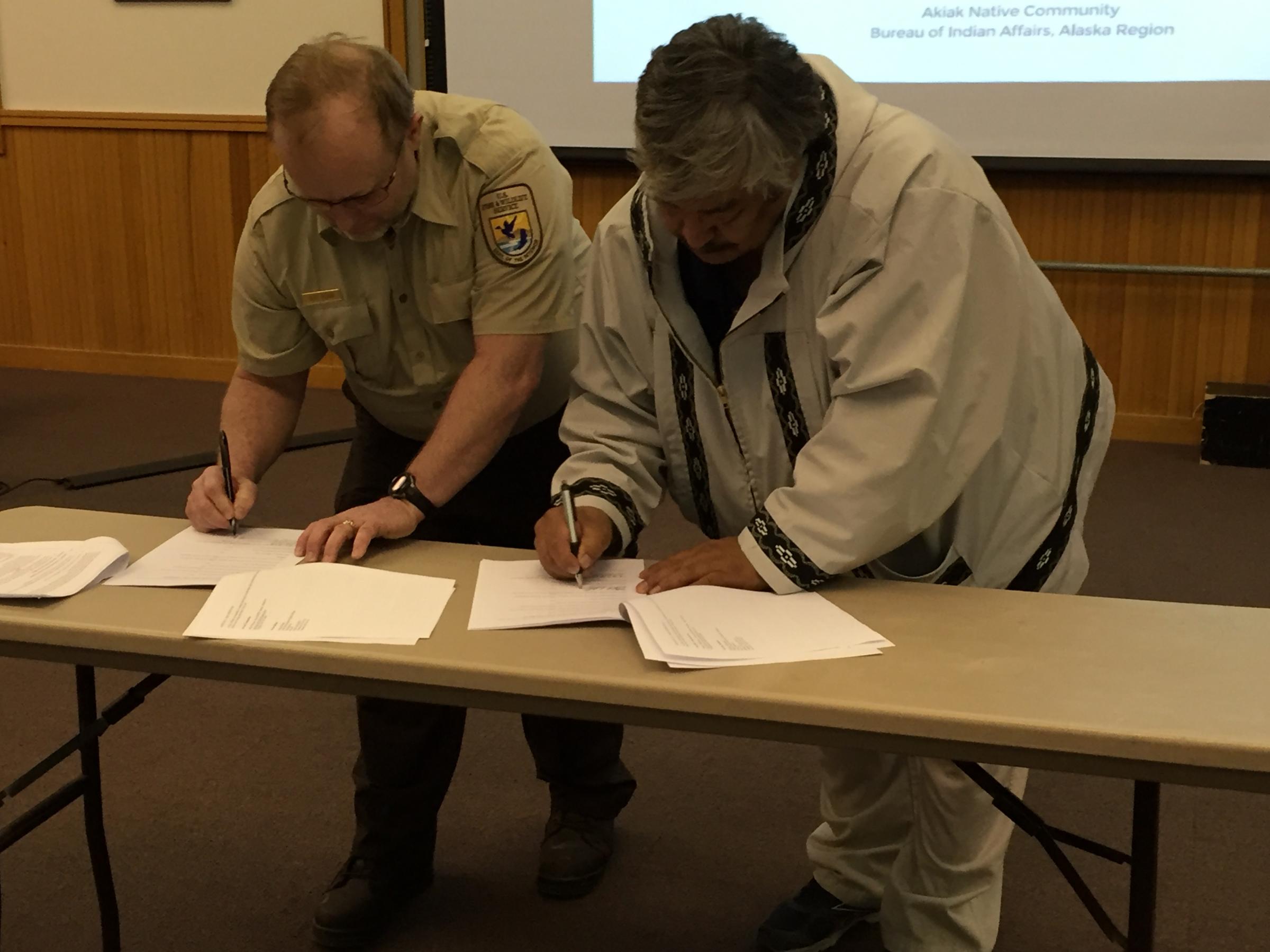 Chair Mike Williams Sr. signs the MOU with USFWS Yukon Delta Refuge Manager Ray Borne. (Photo by Charles Enoch, KYUK - Bethel)