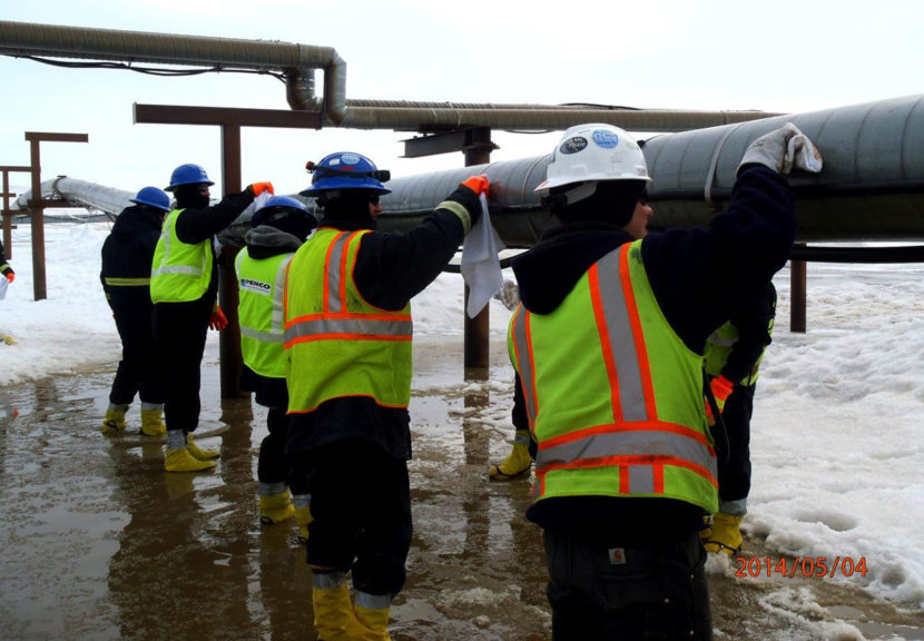 Cleanup personnel wipe oil from well piping on May 4, 2014 where a BP Exploration Alaska pipe ruptured and contaminated nearby tundra. (Photo by Don Fritz/ADEC)