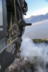 Sgt. Adam Weber, a crew chief with A Co., 1st Battalion, 207th Aviation Regiment, looks onto the McHugh Creek Fire during operations in support of wildfire suppression efforts near Anchorage, July 20, 2016. (U.S. Army National Guard photo by Staff Sgt. Balinda O’Neal Dresel)