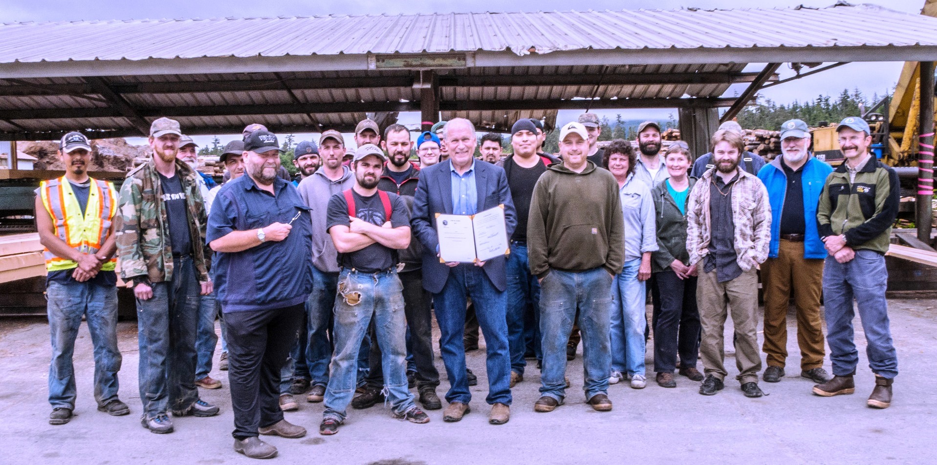 Gov. Bill Walker poses with mill workers July 16 at Viking Lumber in Klawock. He’s holding a bill he signed that could increase the mill’s timber supply. (Photo courtesy of the governor’s office)