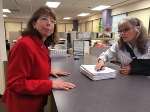 Margaret Stock, left, turns in nominating signatures. Clerk Deborah Moody-Herrera accepted them. Next they'll be sent to Juneau for verification. Photo: Liz Ruskin/Alaska Public Media