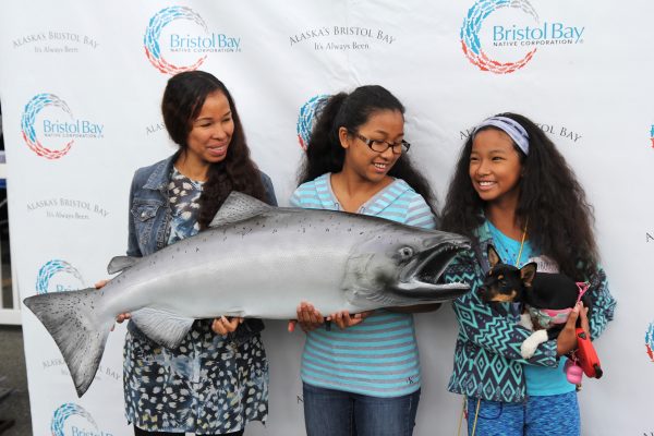 (Left to right) Danya Nickita, Mariah Kiljoha and Isis Kiljoha pose for a photo at a community cookout hosted by the Bristol Bay Native Corporation celebrating Salmon Day in Anchorage on August 10. (Photo by Graelyn Brashear - KSKA/Anchorage)