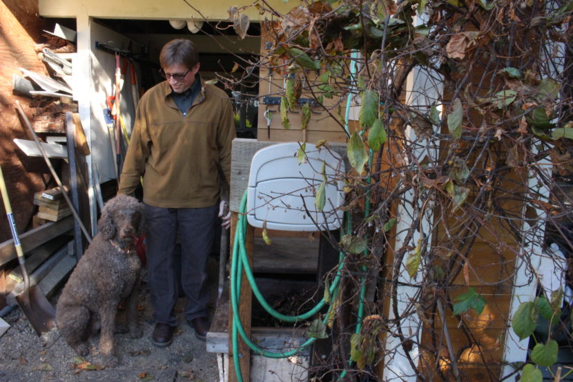 Bob Deering at his home with his dog and compost bins. (Photo by Elizabeth Jenkins, Alaska's Energy Desk - Juneau)