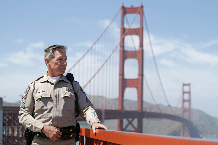 In this photo taken Tuesday, April 30, 2013 California Highway Patrol Sergeant Kevin Briggs poses by the Golden Gate Bridge in San Francisco. About 1,500 people have plunged from the bridge, making it one of the worlds favorite suicide spots. During his 20 years patrolling the bridge Briggs has managed to talk many despondent people out of taking the fatal fall. (AP Photo/Eric Risberg)