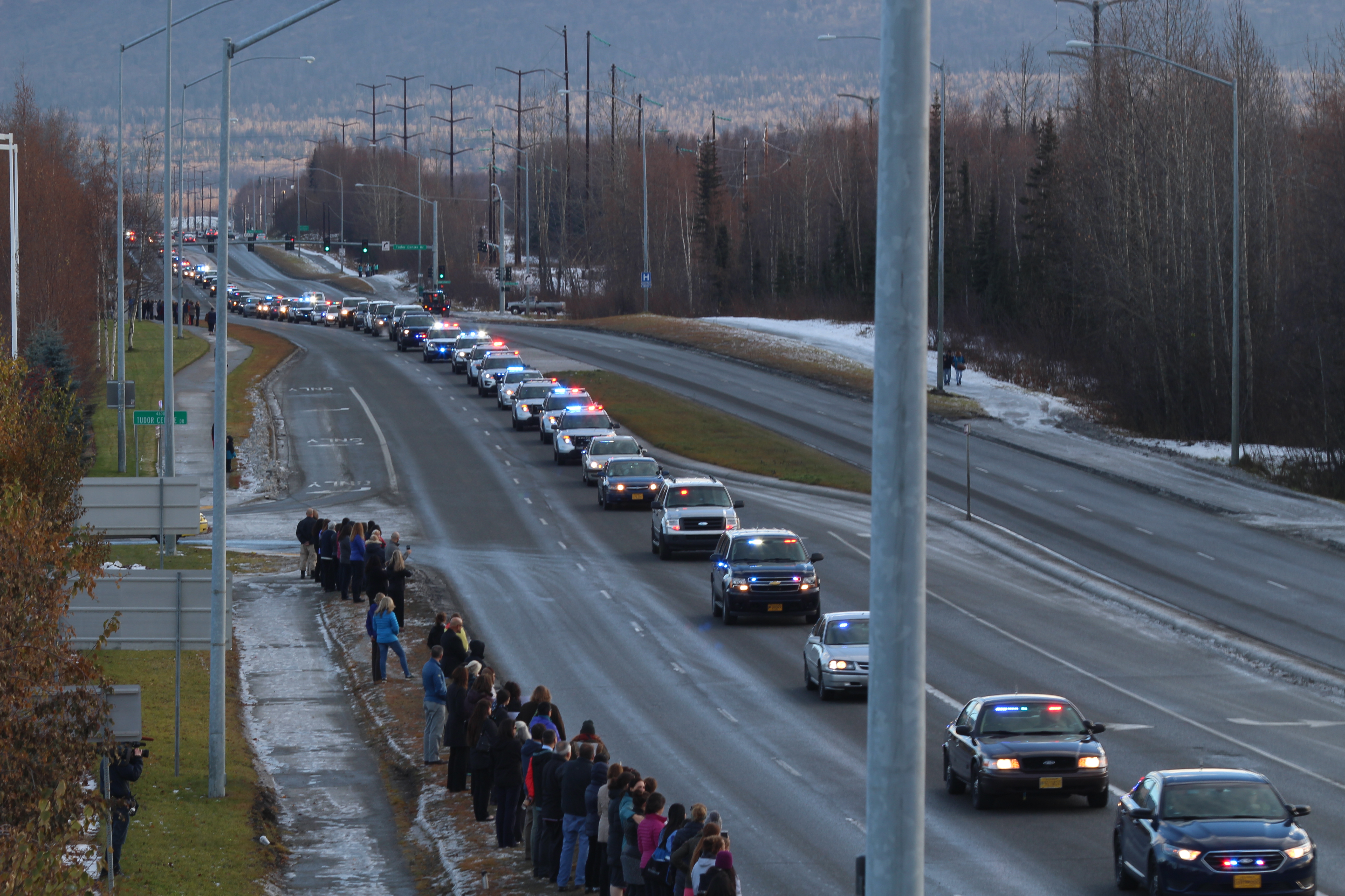 Anchorage citizens watch as a police escort brings Sgt. Allen Brandt's body to Ted Stevns International Airport (Photo by Wesley Early, Alaska Public Media - Anchorage)