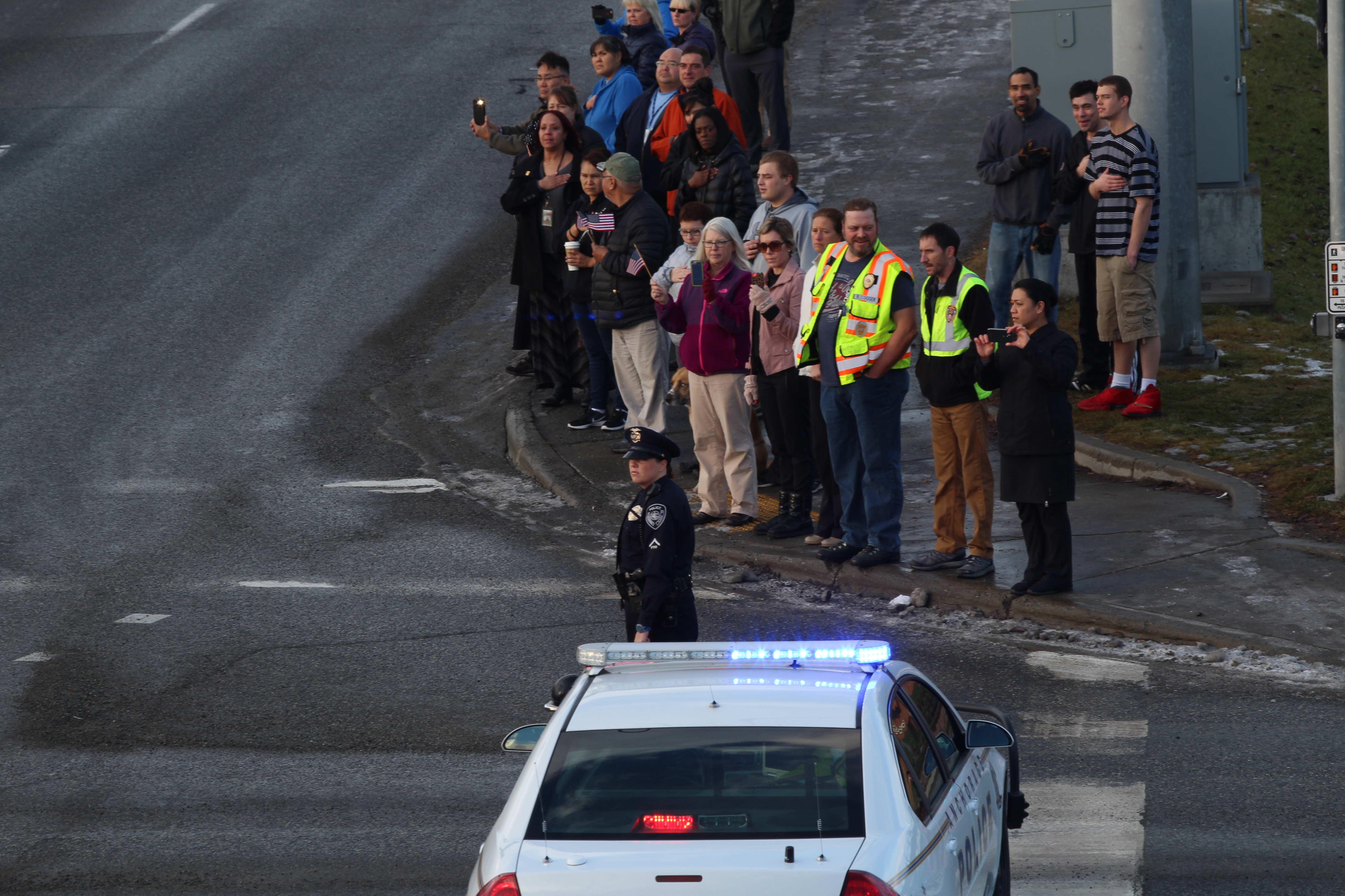 Police block off Tudor road as the procession for Allen Brandt moves through. Citizens stand to the side and watch. (Photo by Wesley Early, Alaska Public Media)