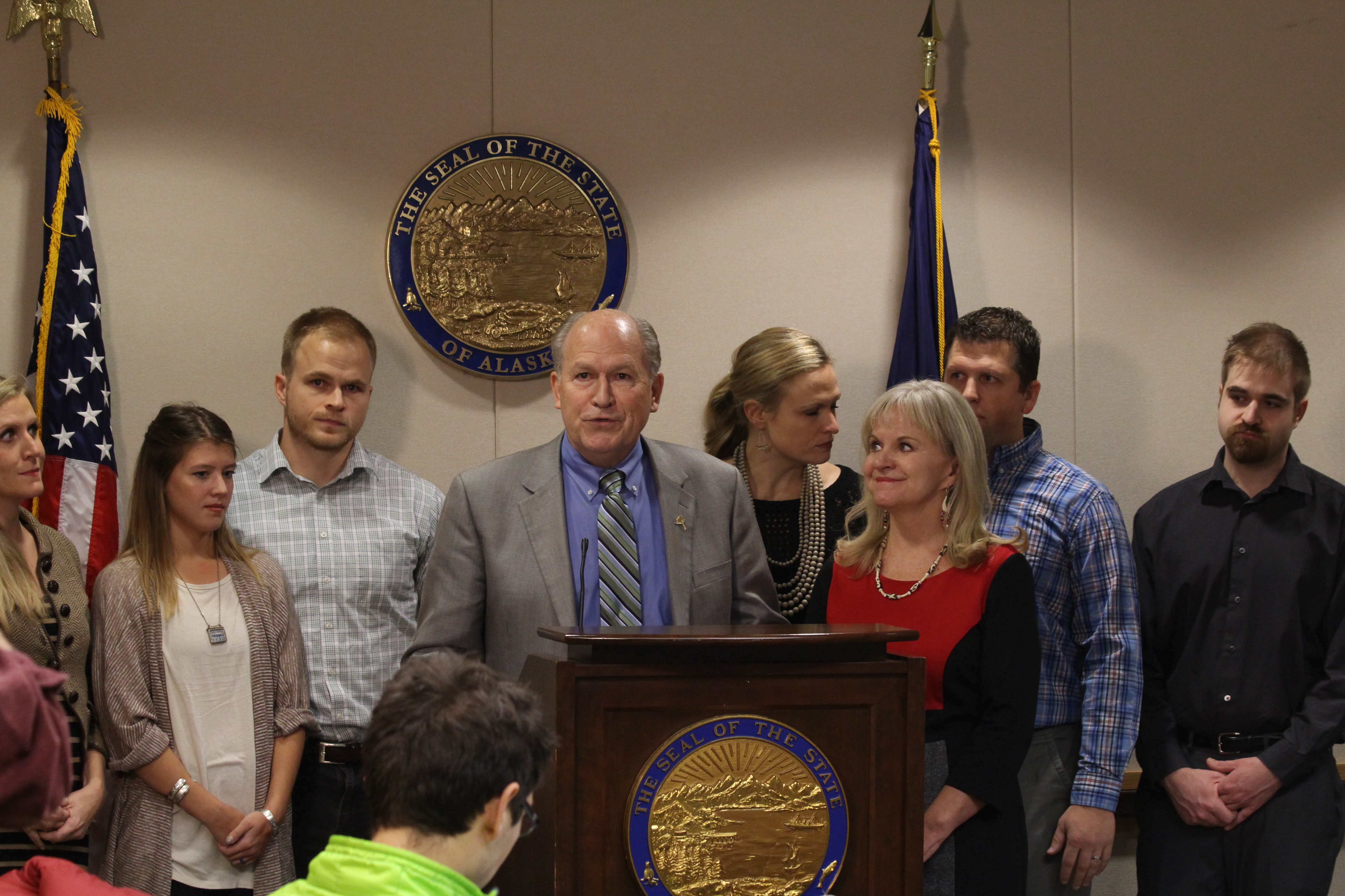 Bill Walker and (from left to right) Tessa Linderman (daughter), Sabrina Walker (daughter-in-law), Adam Walker (son), Lindsay Hobson (daughter), First Lady Donna Walker, Greg Hobson (son-in-law) and Jordan walker (son), as Governor Walker talks to press about his prostate cancer diagnosis. Not pictured: Lt. Governor Byron Mallott and Walker's brother Bob Walker. (Photo by Wesley Early, Alaska Public Media - Anchorage)