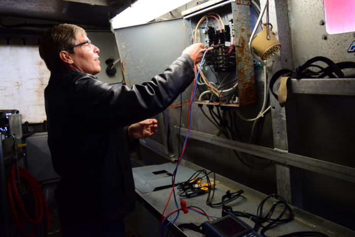 Mike Gaffney connects the power quality analyzer to the fishing vessel’s electric panel. (Photo courtesy of Sustainable Southeast Partnership/Bethany Goodrich.)