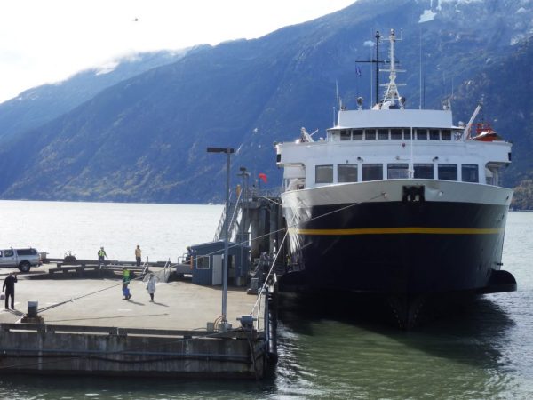 A ferry parked at a dock, a mountain in the background.