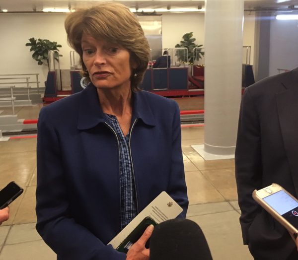 Sen. Lisa Murkowski with three recording devices in the foreground, held by people not in image.