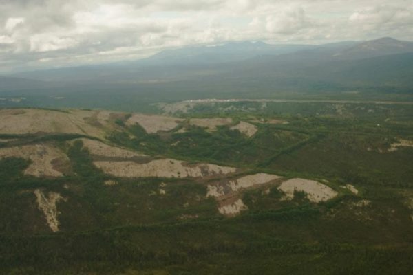 An aerial view of a mining camp, which looks like a clearing in the trees