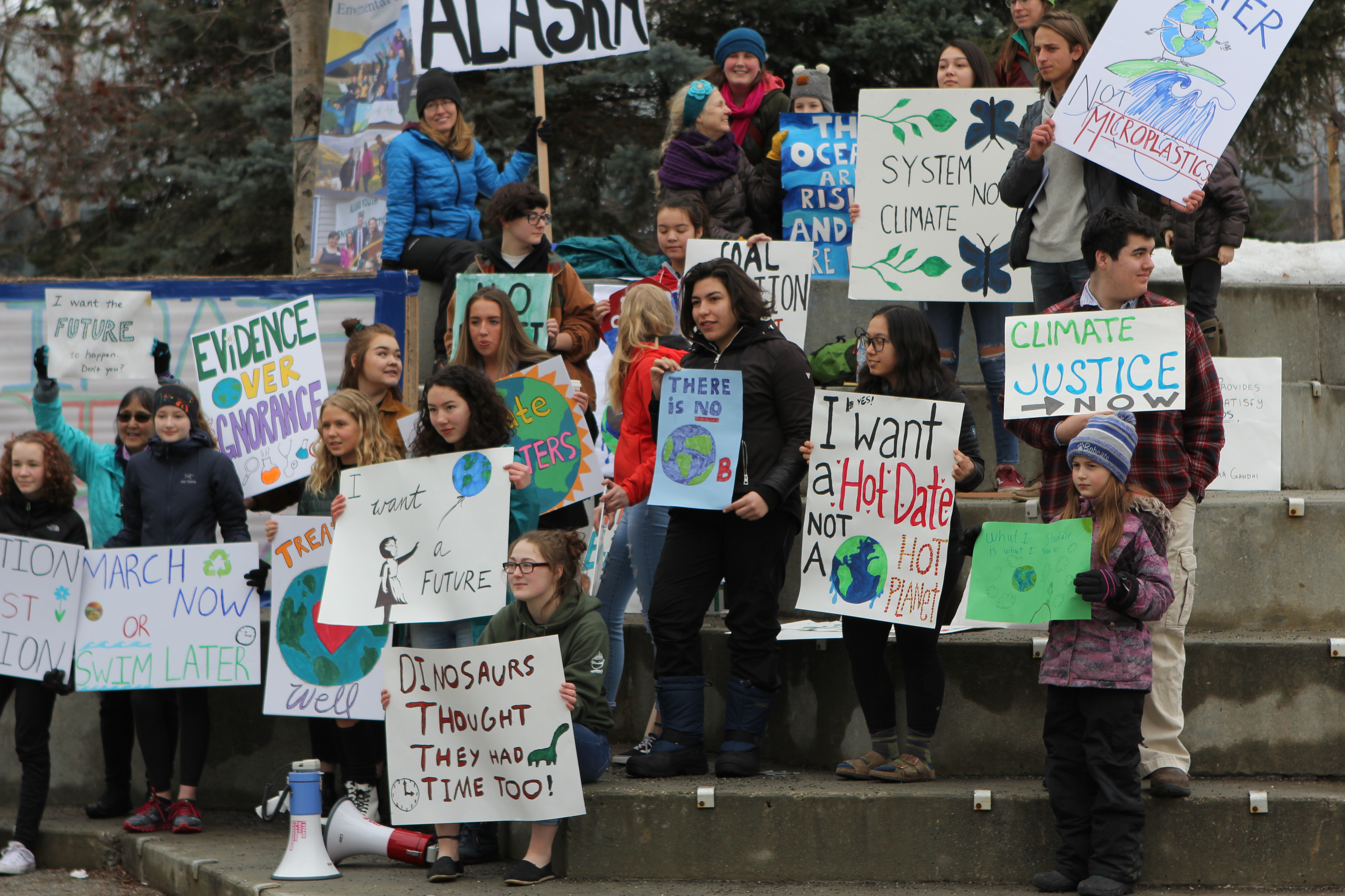 A crowd of young people with signs protesting climate change inaction.