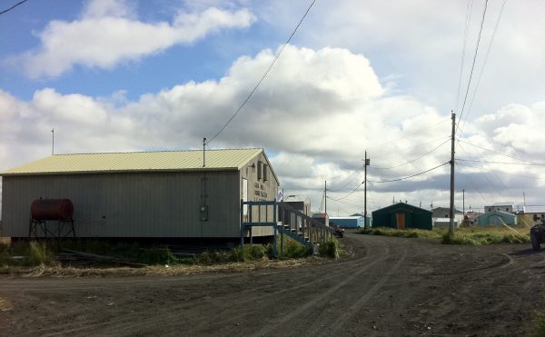A grey building on a dirt road