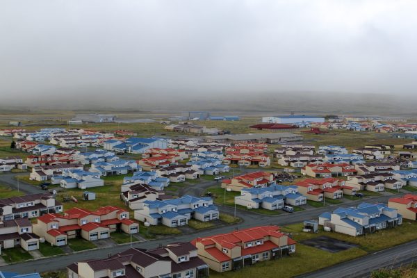 Homes clustered in the grass, under a cloud