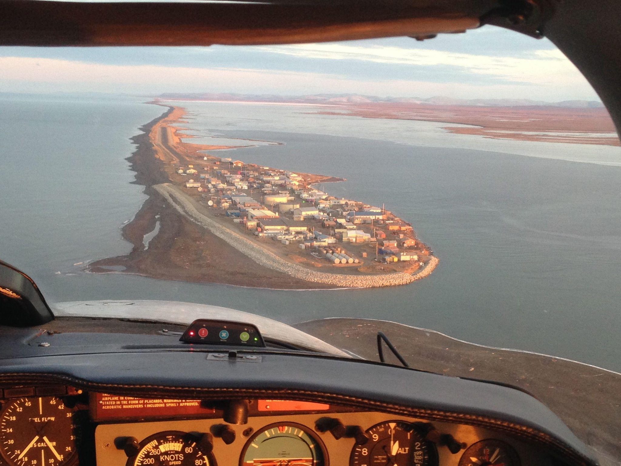 A view of a village at the end of a spit as seen through an airplane cockpit