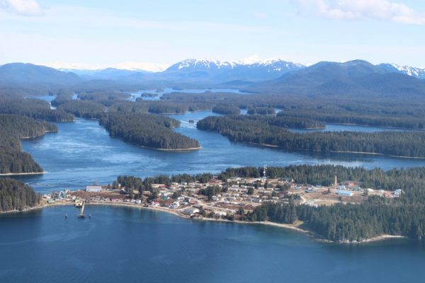 An aerial image of Angoon shows buildings on a small peninsula next to several other inlets.