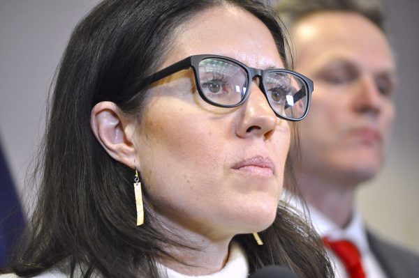 Close up shot of a woman with dark hair and eyeglasses looking into the distance