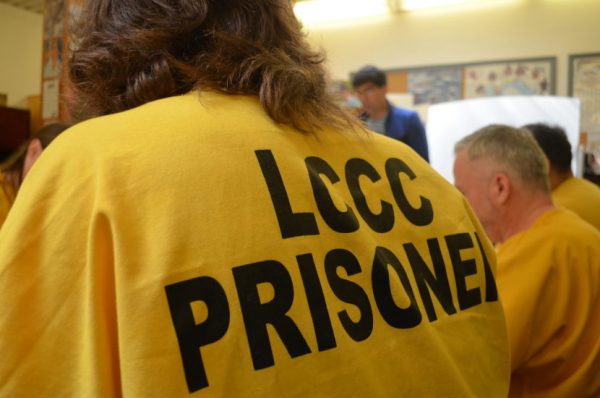 A person in a yellow suit marked LCCC prisoner as seen from behind