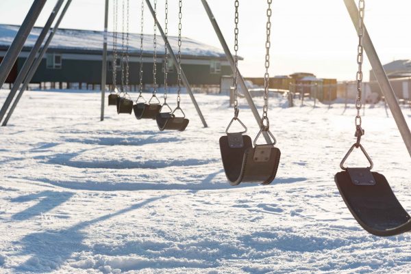 Empty swings in front of a school on a winter day